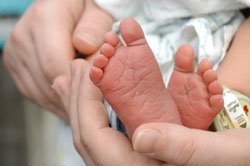 tiny baby feet cradled in his mother's hands